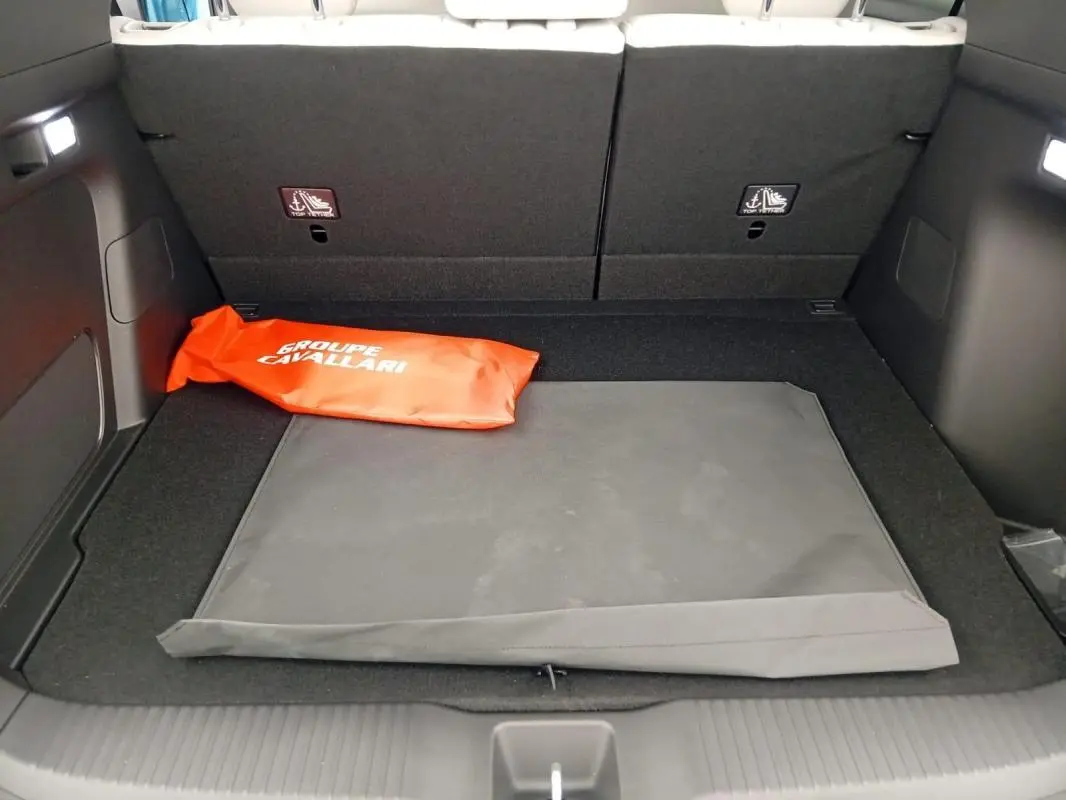 Coffre ouvert du Honda e:Ny1 204 ch Advance 2025, vue intérieure montrant un tapis noir et une trousse orange.