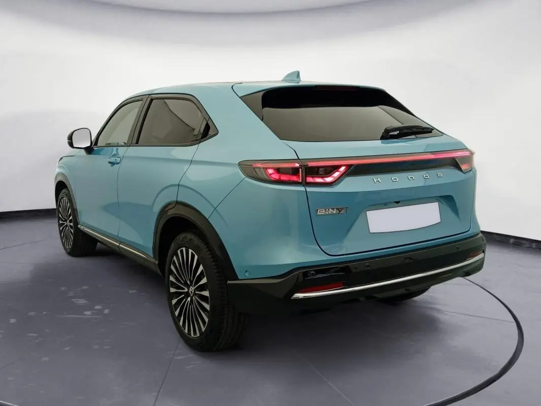 Vue 3/4 arrière droite d'un Honda e:Ny1 Advance 204 ch bleu électrique avec feux arrière LED et jantes stylisées.