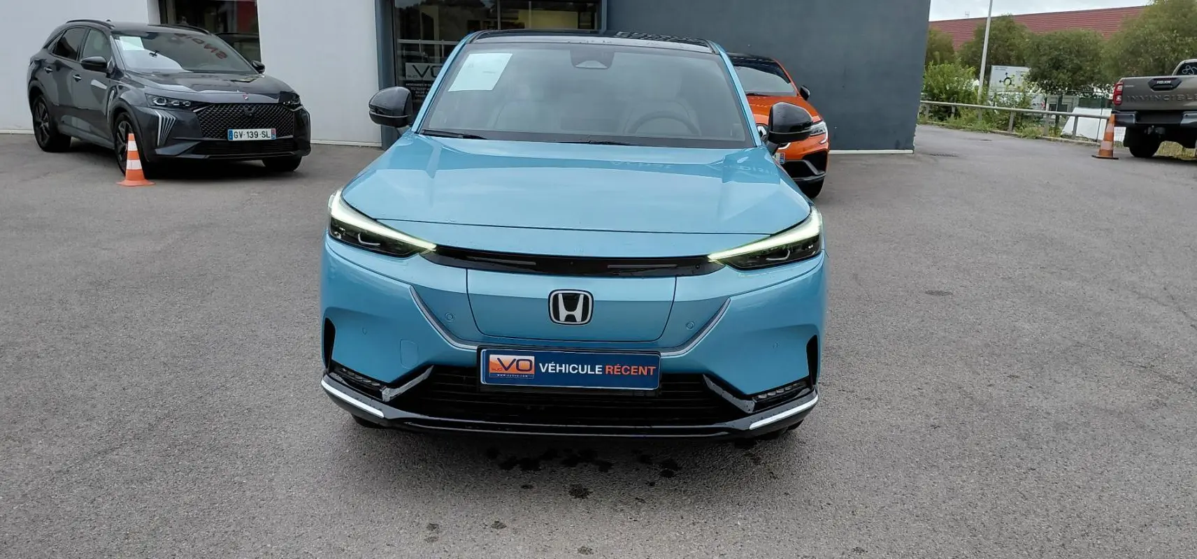 Vue de face du Honda e:Ny1 204 ch Advance bleu électrique 2025 avec phares LED fins et calandre épurée.