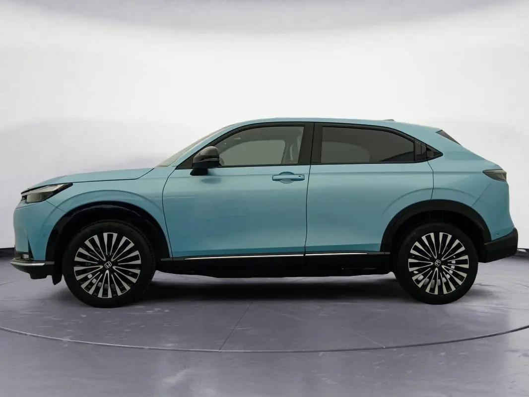Vue latérale gauche du Honda e:Ny1 204 ch Advance 2025 en bleu, avec jantes distinctives bicolores et lignes épurées.