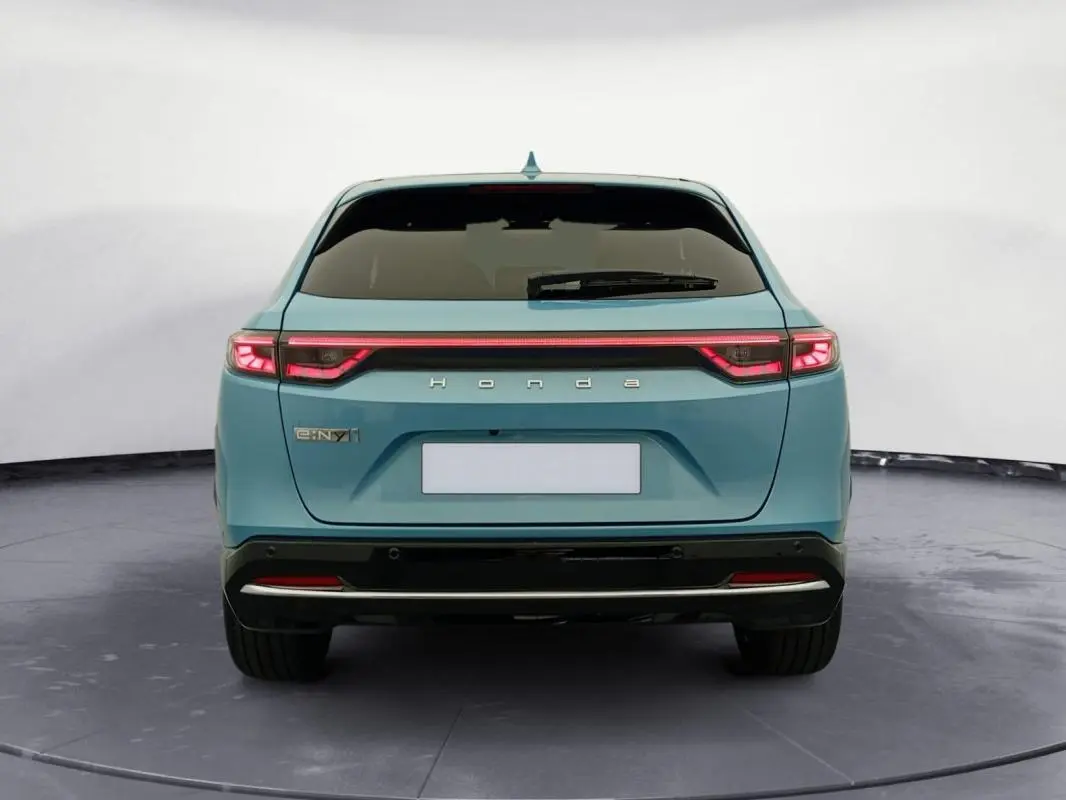 Vue arrière d'une Honda e:Ny1 Advance 204 ch 2025 en bleu avec feux arrière LED reliés par une bande lumineuse.