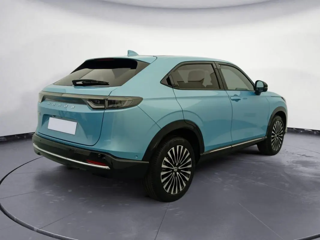 Honda e:Ny1 204 ch Advance 2025 bleu électrique, vue 3/4 arrière droit, jantes stylisées et lignes épurées.