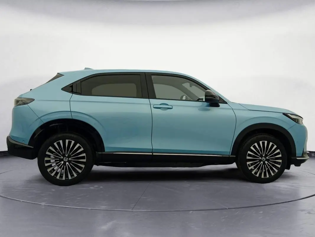 Vue de profil côté gauche d'un Honda e:Ny1 204 ch Advance bleu électrique avec jantes stylisées en étoile.
