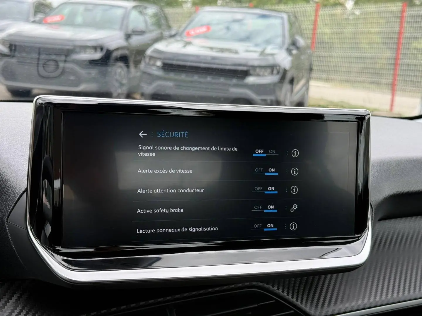 Écran tactile central de la Peugeot 208 noir Perla Nera, vue intérieure avant avec menu sécurité affiché.