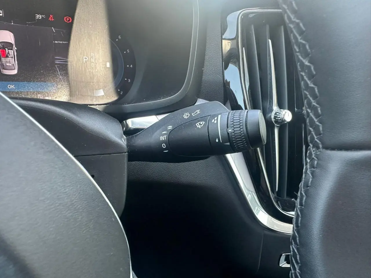 Gros plan sur la commande d'essuie-glace à gauche du volant dans l'habitacle noir du Volvo S60 2024 Thunder Grey Metal