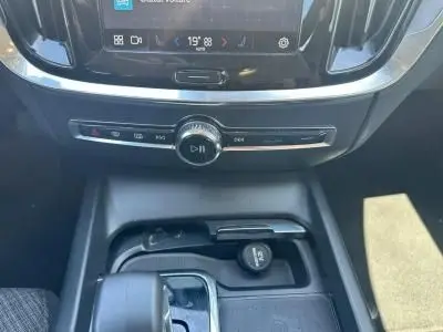 Gros plan sur la console centrale noire du Volvo S60 2024 avec commandes multimédia et prise 12V visible