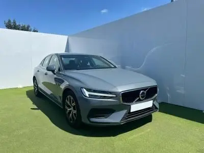 Volvo S60 2024 Thunder Grey Metal vue 3/4 avant avec calandre chromée et jantes alliage noires sur fond clair.