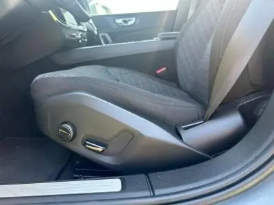 Gros plan sur le siège conducteur gris foncé de la Volvo S60 2024, montrant les commandes électriques sur le côté gauche.