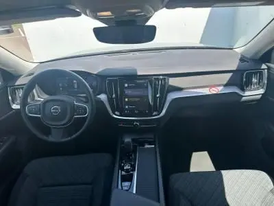 Intérieur avant de la Volvo S60 2024 en Thunder Grey Metal, tableau de bord avec écran tactile central et volant multifonction.