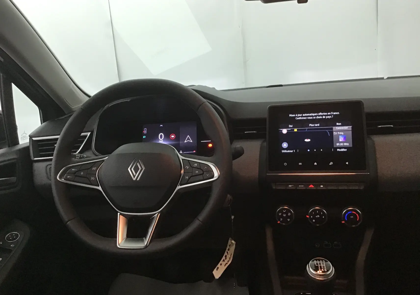 Vue intérieure centrée sur le volant Renault Clio V 2025 avec écran tactile et levier de vitesse manuel.