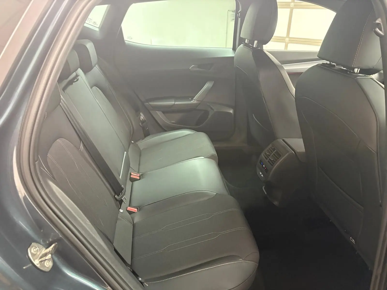 Vue intérieure côté arrière droit du CUPRA Formentor gris magnétique 2024, sièges cuir noirs avec surpiqûres contrastées.