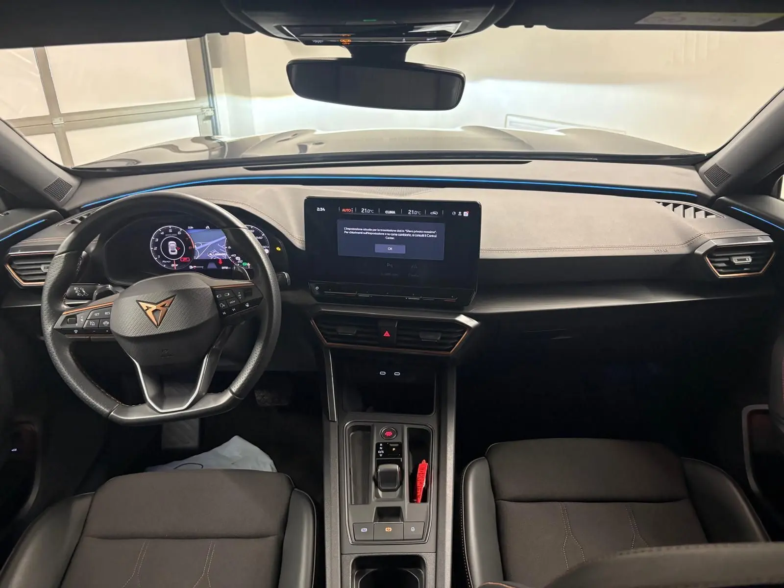 Vue intérieure frontale du tableau de bord du CUPRA Formentor 2024 avec éclairage d'ambiance bleu et écran tactile central.