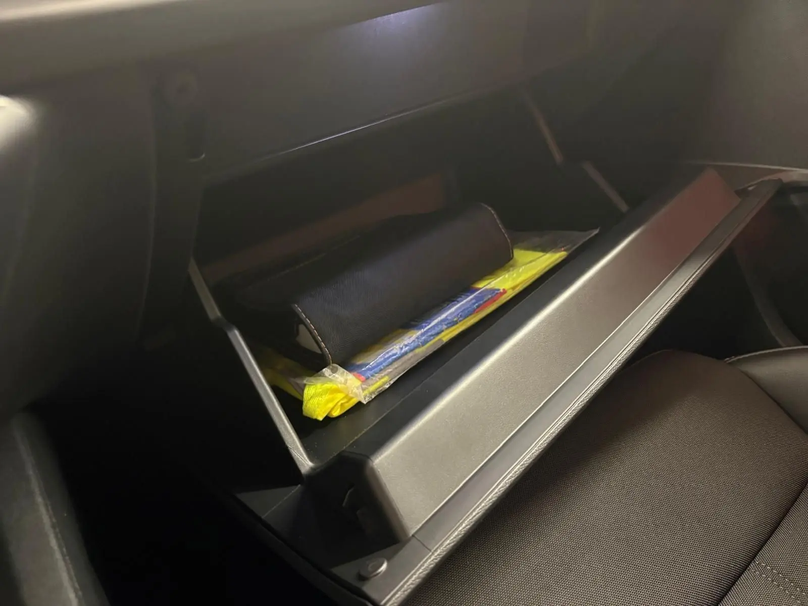 Gros plan sur la boîte à gants ouverte du CUPRA Formentor 2024, contenant des documents et accessoires, intérieur noir.