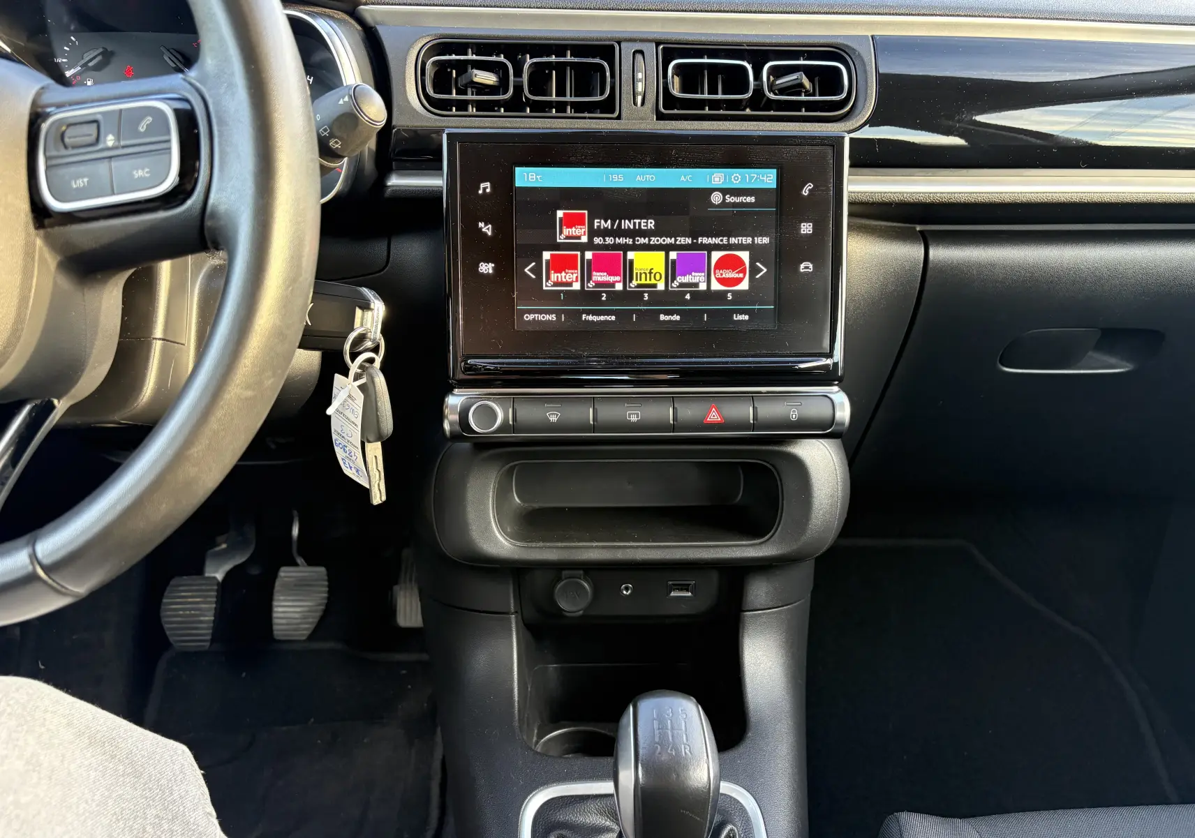 Vue intérieure centrée sur la console centrale et le volant gauche de la Citroën C3 1.2 PureTech rouge avec boîte manuelle et écran tactile.