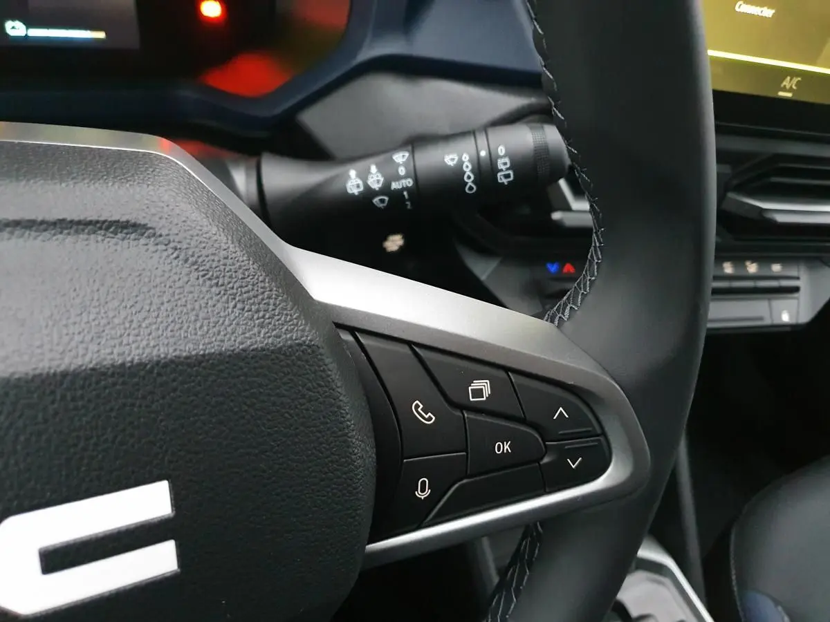 Gros plan sur le volant noir du Dacia Duster 2025 avec commandes multifonctions et tableau de bord partiel.