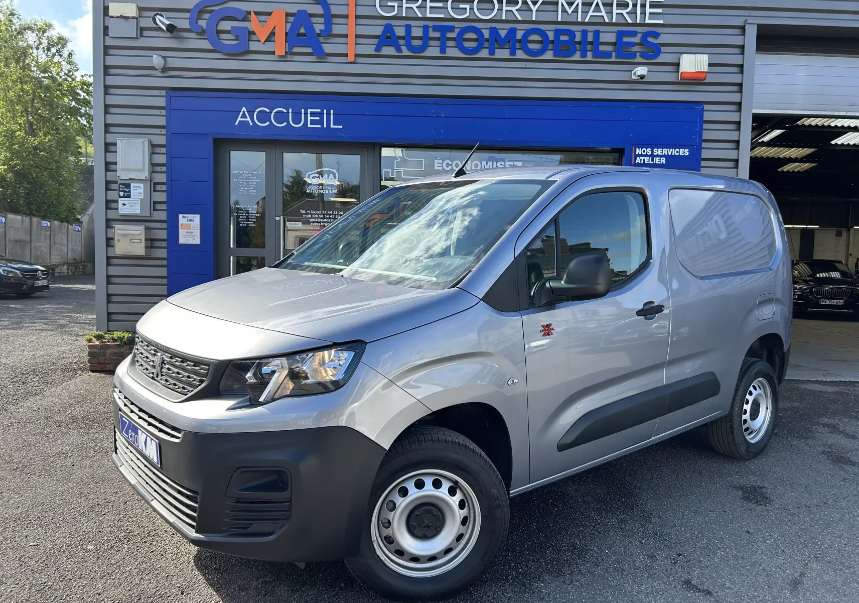 Vue 3/4 avant droit du Peugeot Partner Dangel 4x4 gris Artense devant un garage Gregory Marie Automobiles.