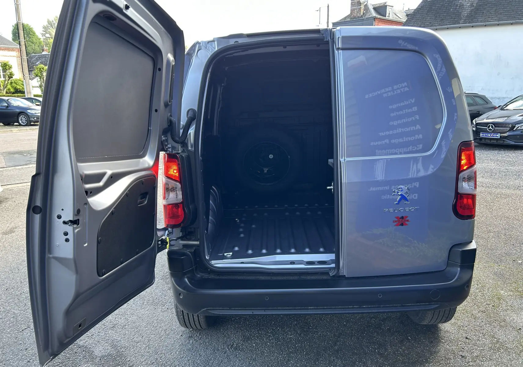 Vue arrière ouverte du Peugeot Partner Dangel 4x4 gris Artense montrant l'espace de chargement vide.