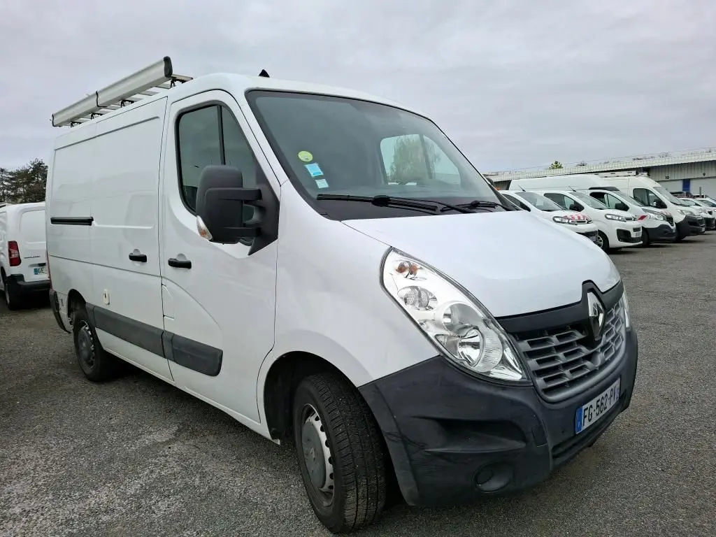 Renault Master blanc en vue 3/4 avant droit, avec galerie de toit et rétroviseurs noirs, stationné parmi d'autres utilitaires.