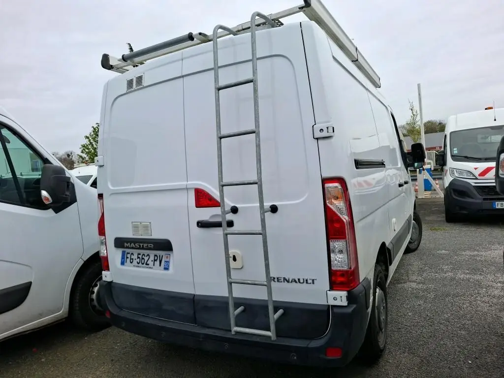 Vue arrière d'un Renault Master blanc 2019 avec échelle métallique fixée sur la porte et galerie sur le toit.