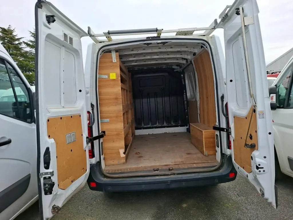 Vue arrière d’un Renault Master blanc 2019 avec portes ouvertes, montrant l’intérieur utilitaire équipé de rangements en bois.
