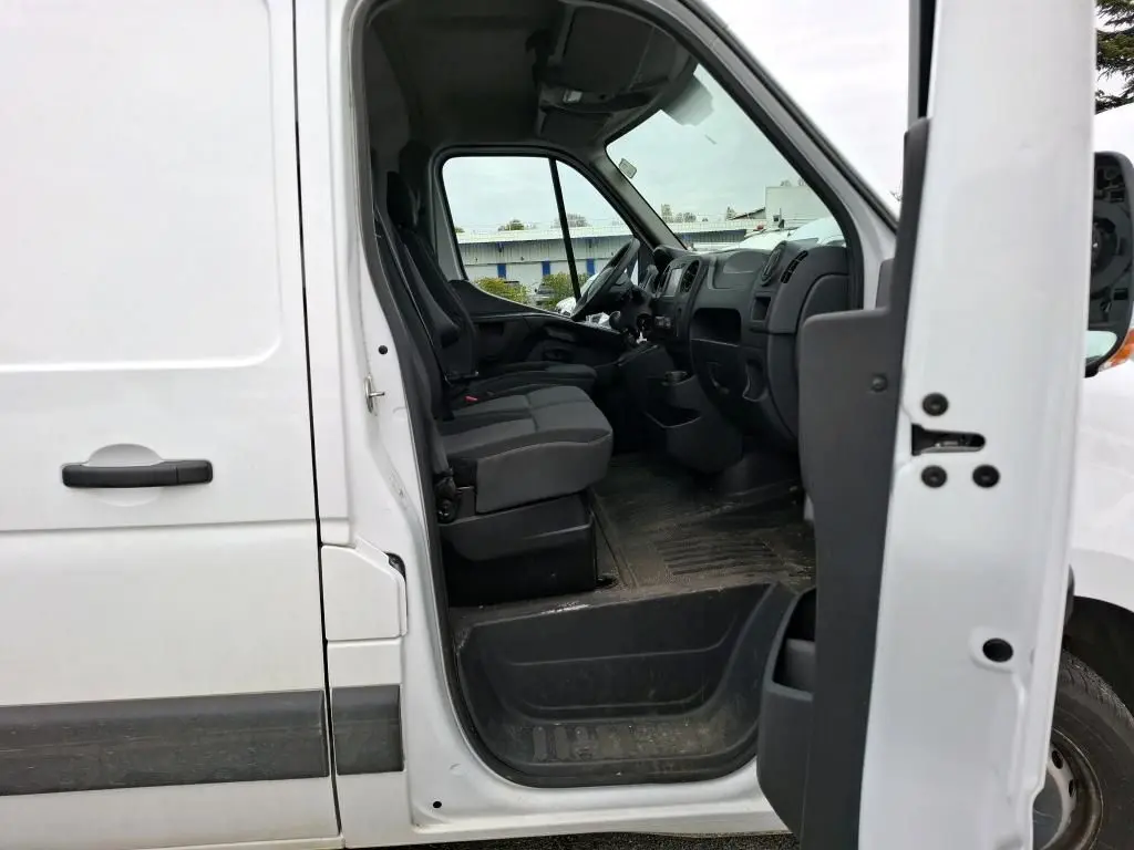 Vue latérale côté gauche du Renault Master blanc 2019 avec porte avant ouverte montrant l'intérieur cabine et les sièges noirs.