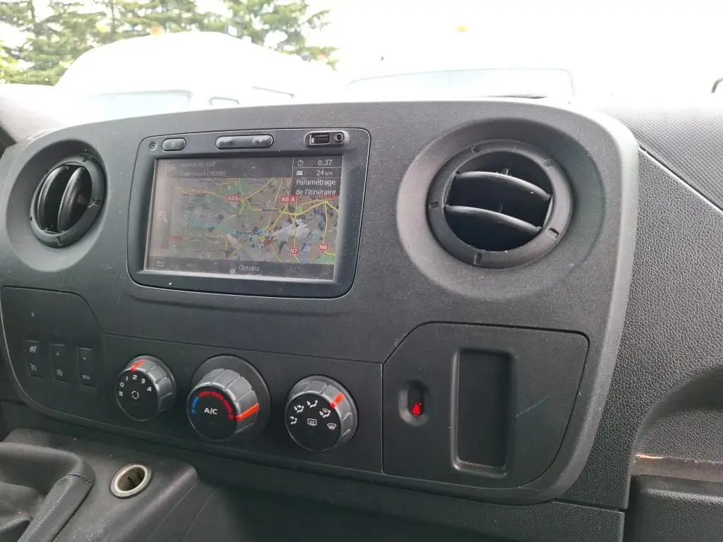 Vue rapprochée de la console centrale du Renault Master blanc, avec écran GPS et commandes de climatisation visibles.