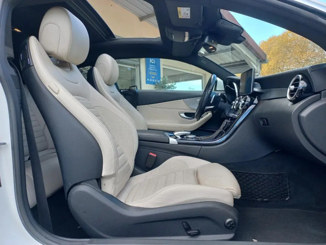 Vue latérale intérieure côté gauche d’une Mercedes Classe C Coupé 2016 avec sièges cuir beige et toit ouvrant électrique.