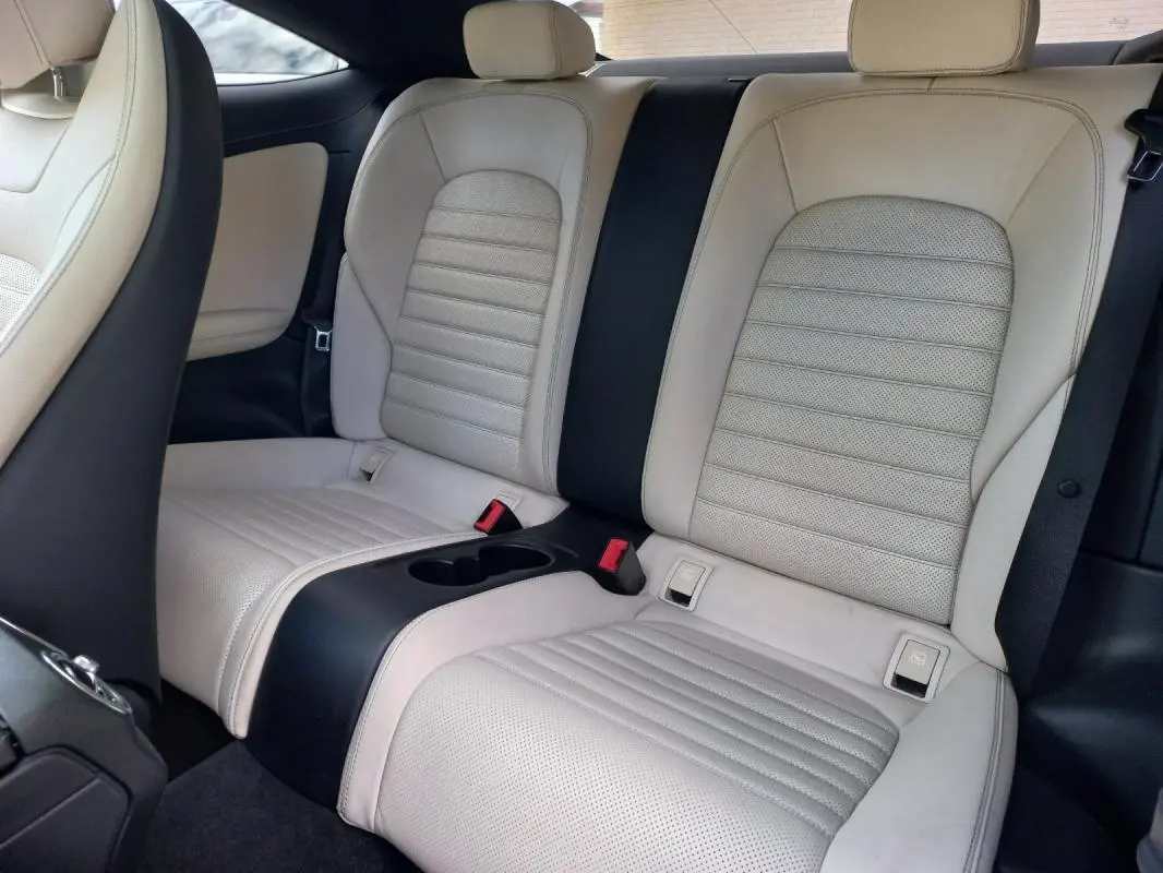 Vue intérieure arrière de la Mercedes Classe C Coupé blanc, sièges en cuir clair avec accoudoir central noir.