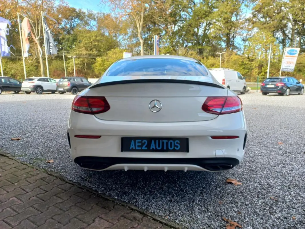 Vue arrière d'une Mercedes Classe C Coupé IV 400 Fascination blanche, avec feux LED et double sortie d'échappement noire.