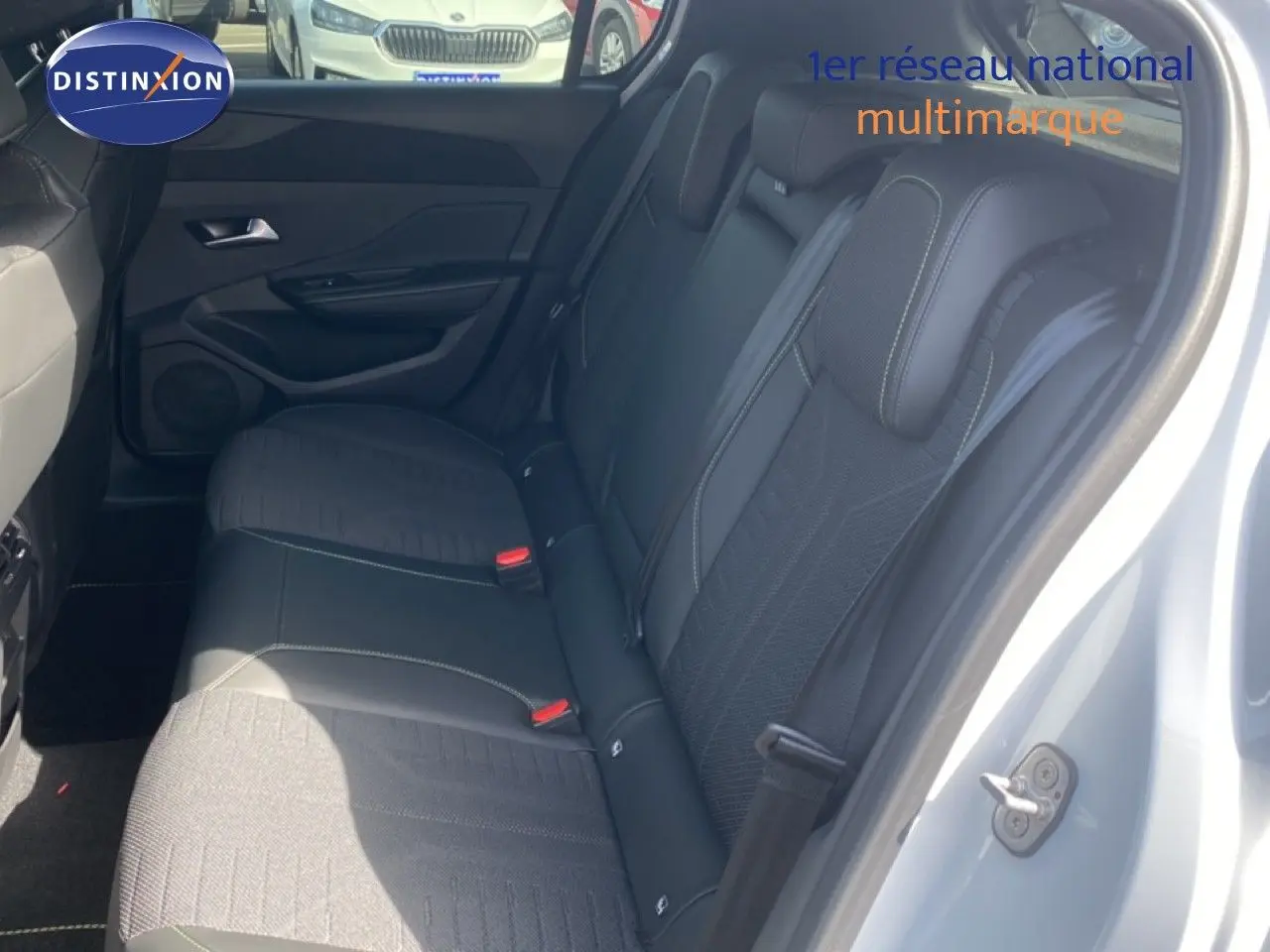 Vue intérieure côté droit montrant la banquette arrière en tissu et cuir noir d'une Peugeot 308 Hybrid 2026 blanc Okenite.