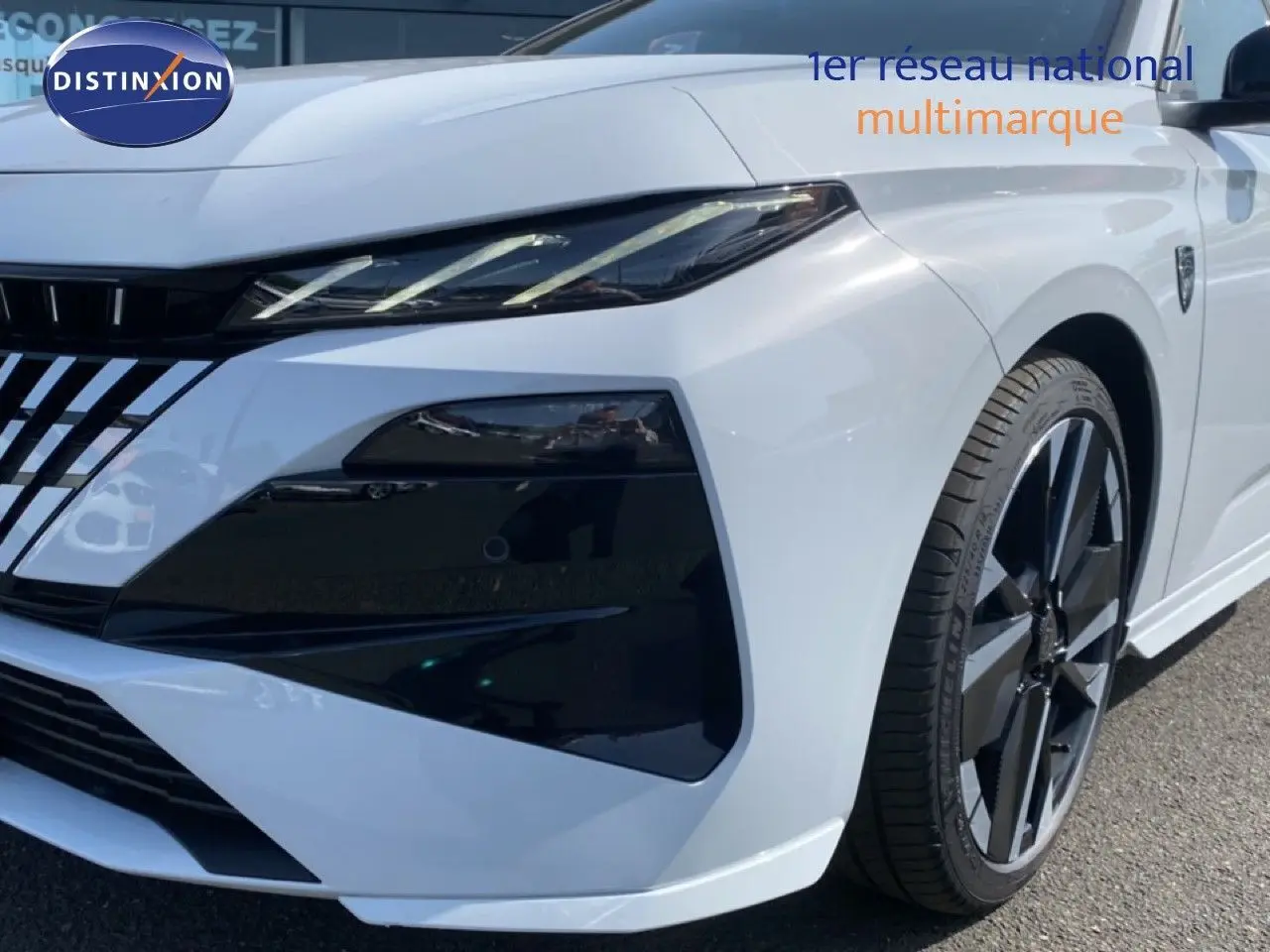 Vue 3/4 avant droit d'une Peugeot 308 Hybrid 145ch GT blanche Okenite Metal avec jantes noires et détails noirs contrastants.