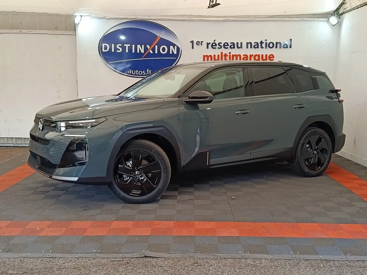 Vue 3/4 avant droit d'un Citroën C5 hybride vert avec jantes noires et calandre moderne dans un showroom.