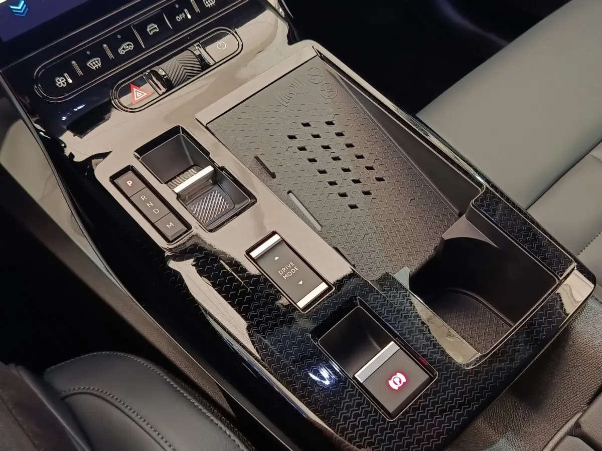 Vue rapprochée de la console centrale noire brillante avec commande de boîte auto et bouton frein à main de la Citroën C5 Hybride.