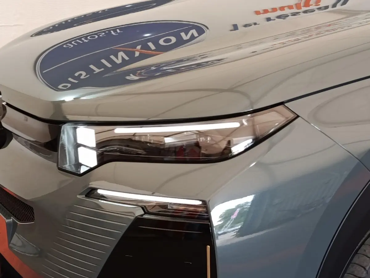 Gros plan sur le phare avant droit du Citroën C5 Hybride vert 2026 avec détails LED et carrosserie brillante.