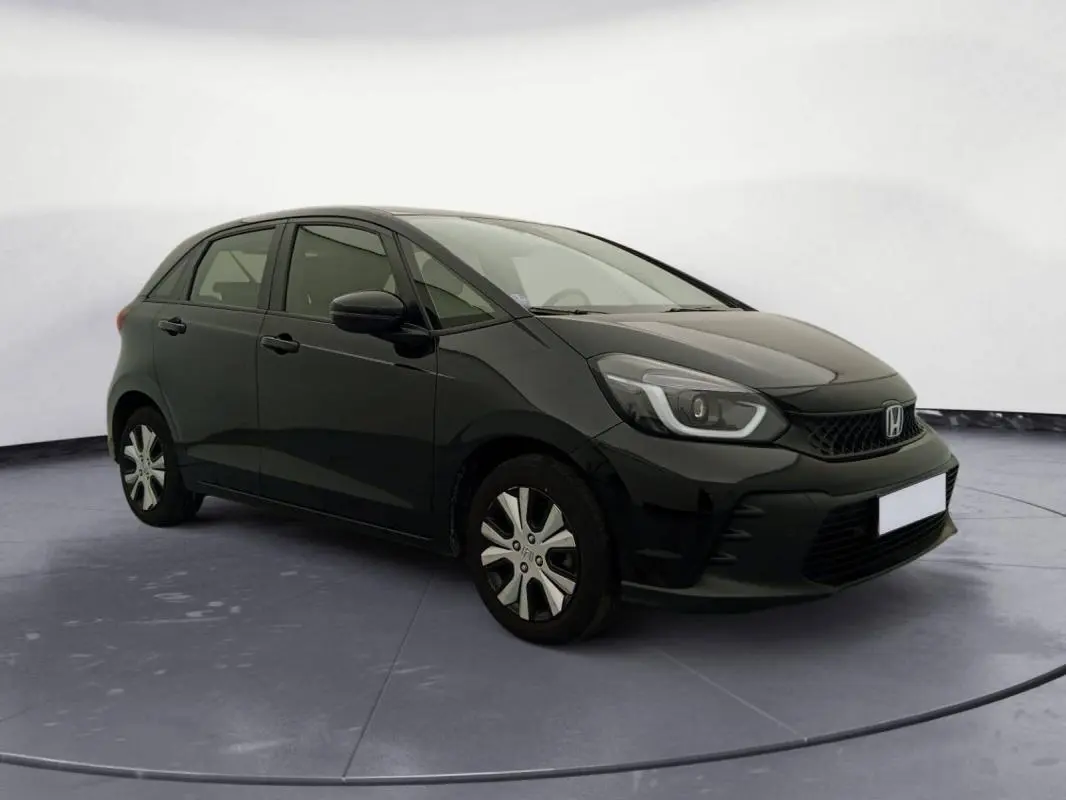 Honda Jazz 2024 noir vue 3/4 avant droit, avec phares LED et jantes spécifiques version hybride essence.