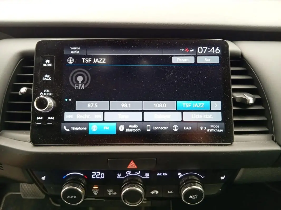 Écran tactile central de la Honda Jazz 2024 noir, affichant la radio FM TSF Jazz, avec commandes climatisation en dessous.