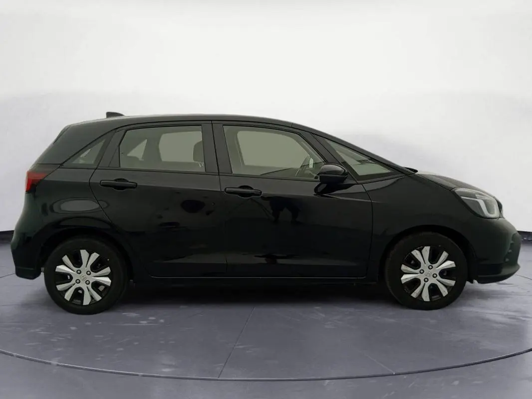 Profil côté gauche de la Honda Jazz 2024 noire, version hybride E:HEV 1.5 i-MMD Advance avec jantes spécifiques.