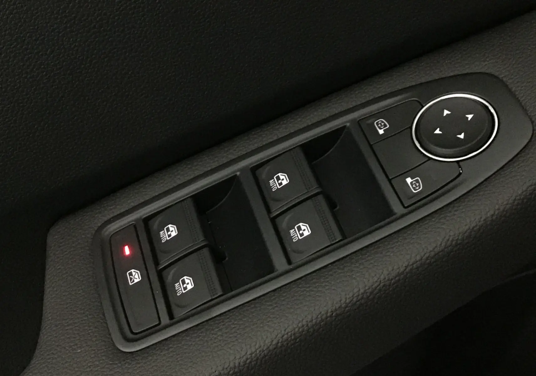 Gros plan sur les commandes de lève-vitres et réglage des rétroviseurs côté conducteur d'une Renault Clio V gris schiste.