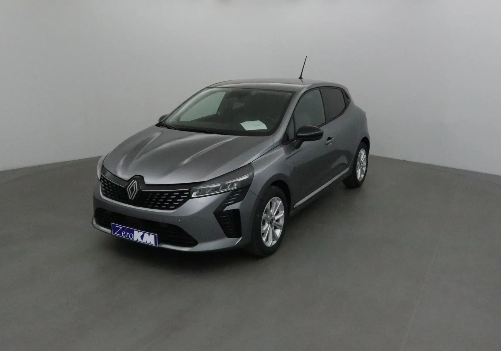 Renault Clio V gris schiste vue 3/4 avant droit, avec protections latérales chromées et jantes alliage 16 pouces.