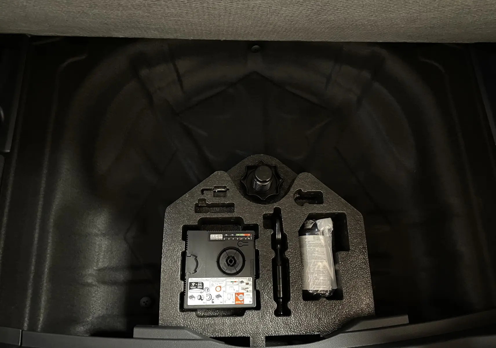 Coffrage d'outils de bord dans le coffre d'un SEAT Ateca 2024, avec compresseur et accessoires rangés.