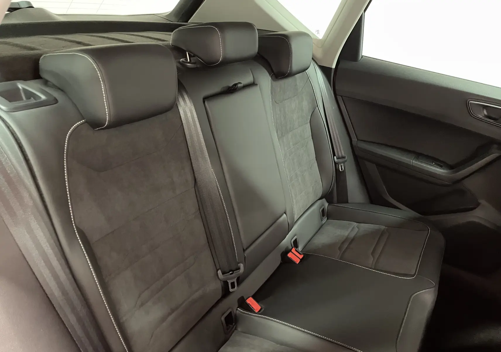 Vue intérieure du siège arrière droit du SEAT Ateca 2024 avec sellerie noire en cuir et alcantara, surpiqûres blanches visibles.