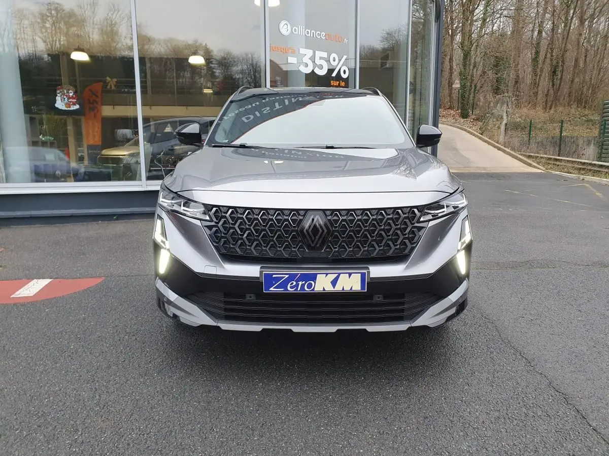 Vue de face du Renault Austral gris schiste avec calandre noire et feux LED allumés, toit panoramique noir visible.