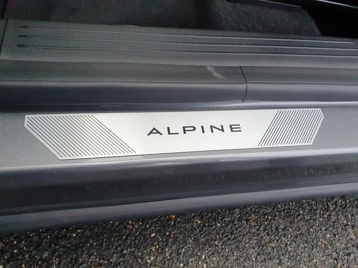 Gros plan sur la plaque de seuil de porte ALPINE du Renault Austral gris schiste avec toit noir visible en arrière-plan.