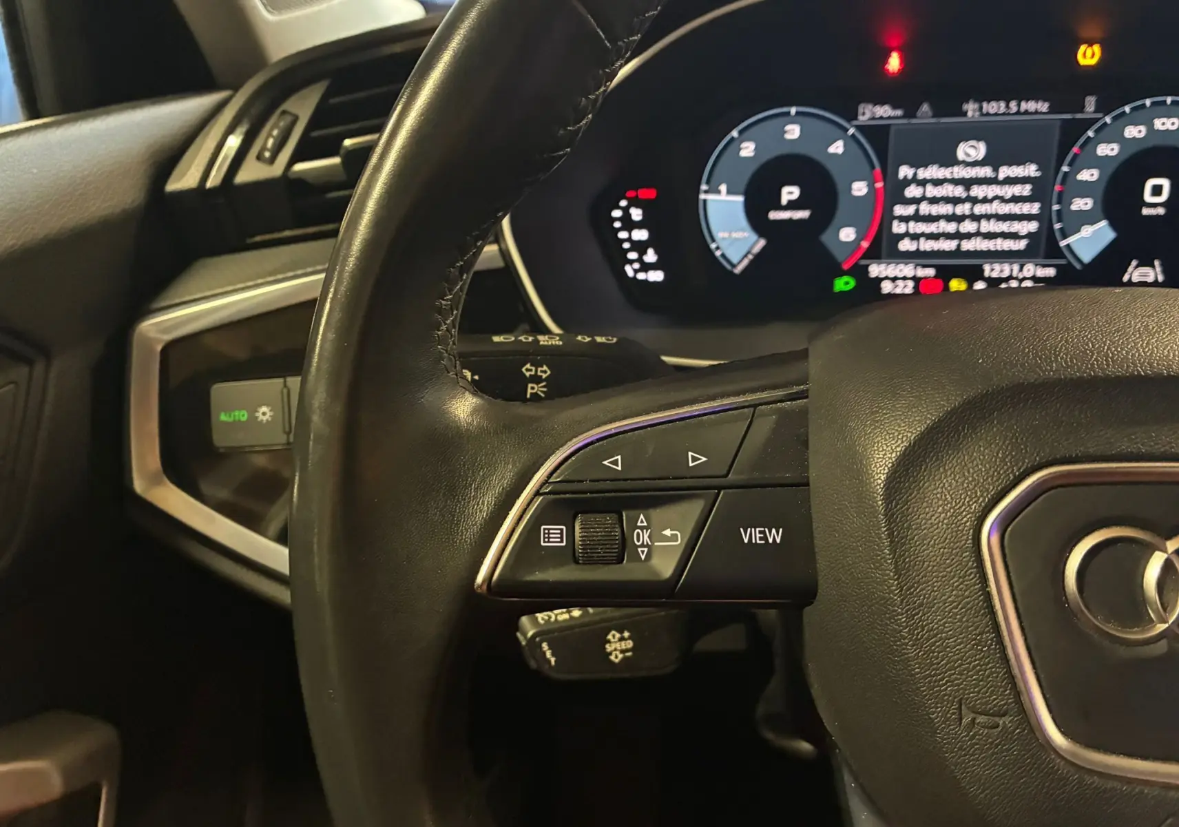 Gros plan sur le volant cuir multifonctions et le tableau de bord numérique de l'Audi Q3 Sportback gris, vue côté conducteur.