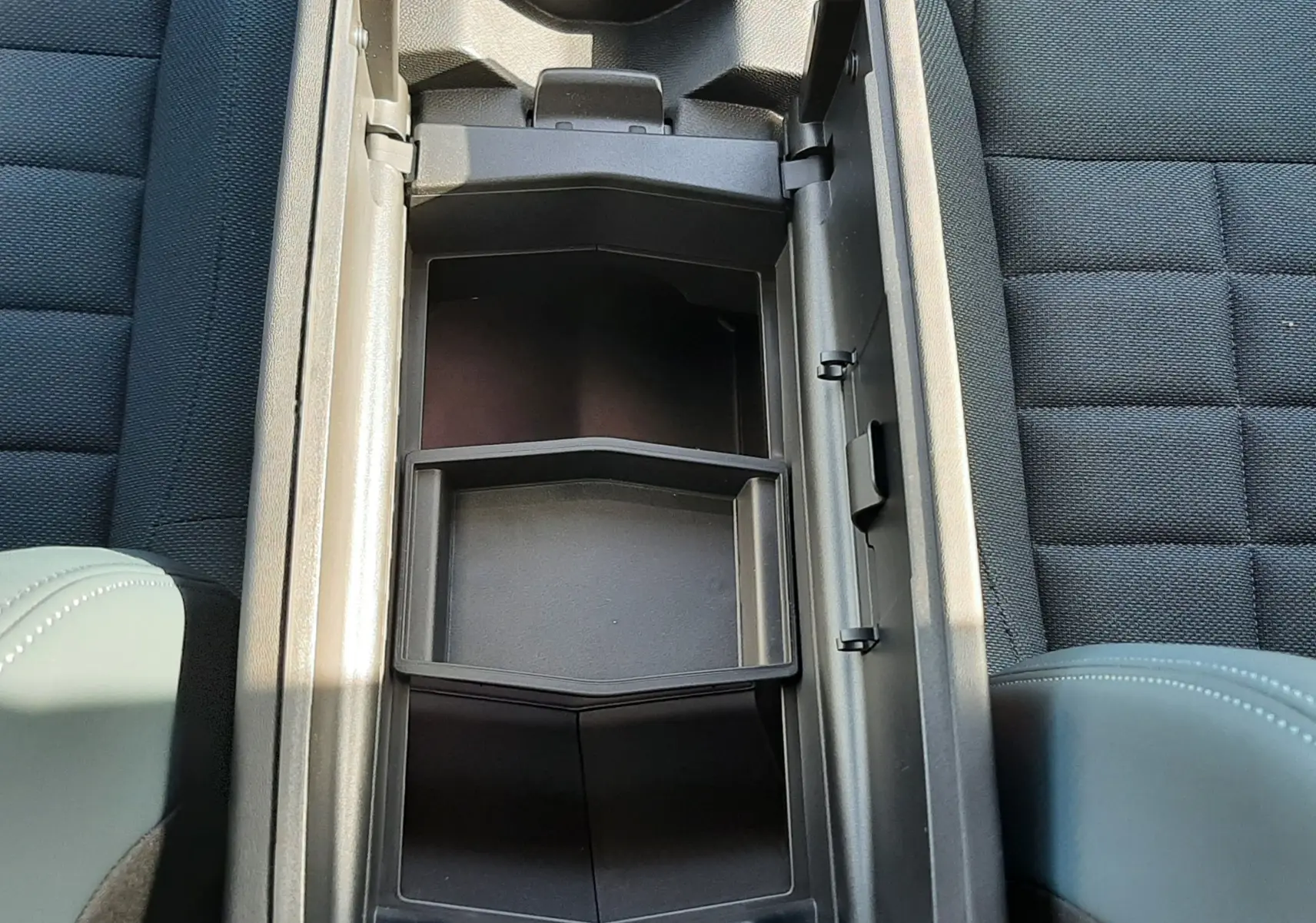 Vue plongeante sur le rangement central ouvert du Citroën C5 Aircross 2026, sièges tissu gris et cuir vert Astoria.