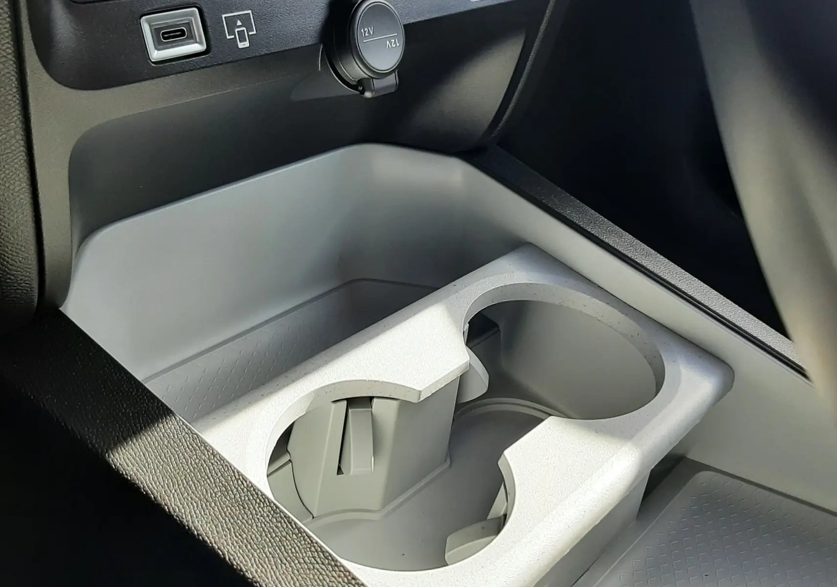 Gros plan sur la console centrale grise du Citroën C5 Aircross 2026, avec porte-gobelets et prises USB et 12V visibles.