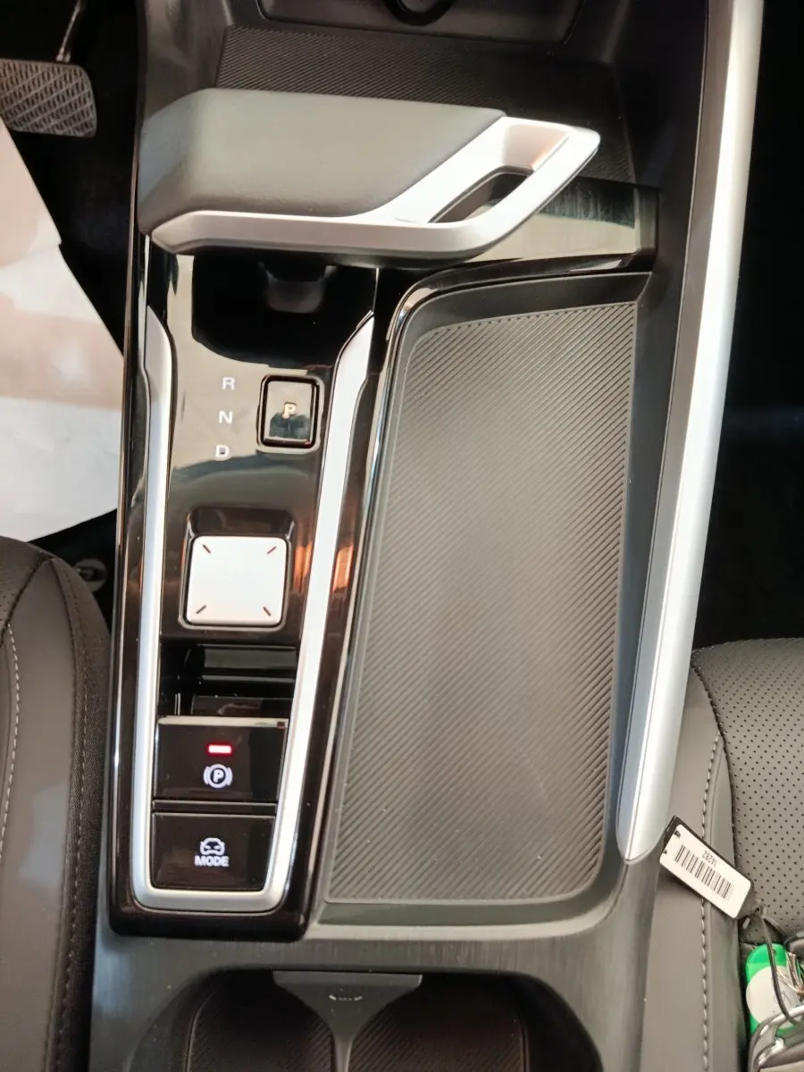 Gros plan sur la console centrale noire et grise du MG ZS Hybrid+ Luxury avec levier de vitesses automatique et bouton parking.