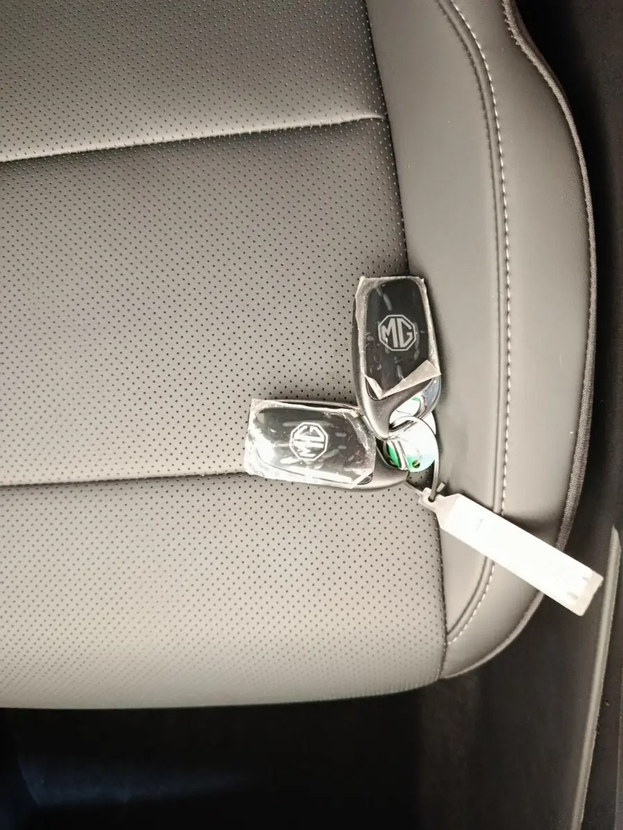 Gros plan sur deux clés MG posées sur un siège en cuir gris perforé à l'intérieur du véhicule.