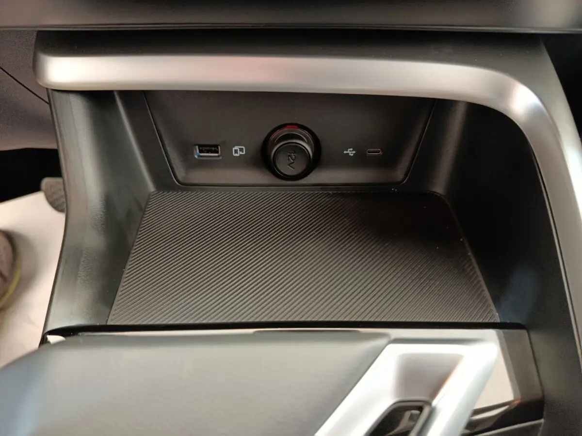 Gros plan sur la console centrale noire du MG ZS Hybrid+ Luxury avec prises USB, prise 12V et surface texturée antidérapante.