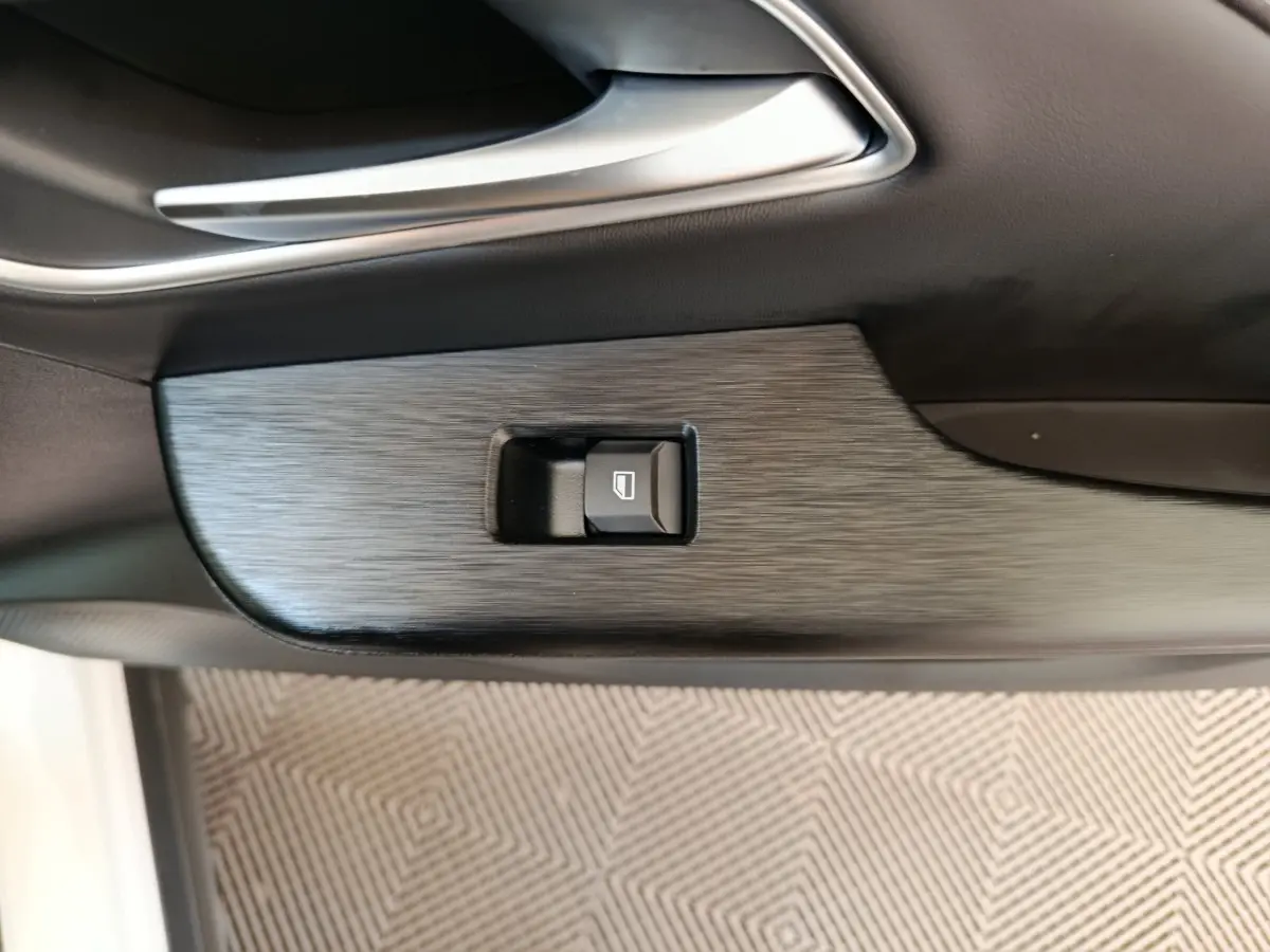 Gros plan sur la commande de lève-vitre intégrée dans la porte intérieure noire du MG ZS blanc.